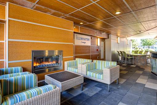 A patio with a fireplace and striped couches.