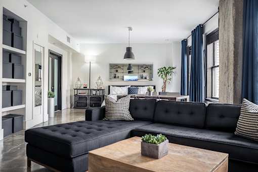 A black tufted sofa sits in a modern living room with a wooden coffee table in front of it.