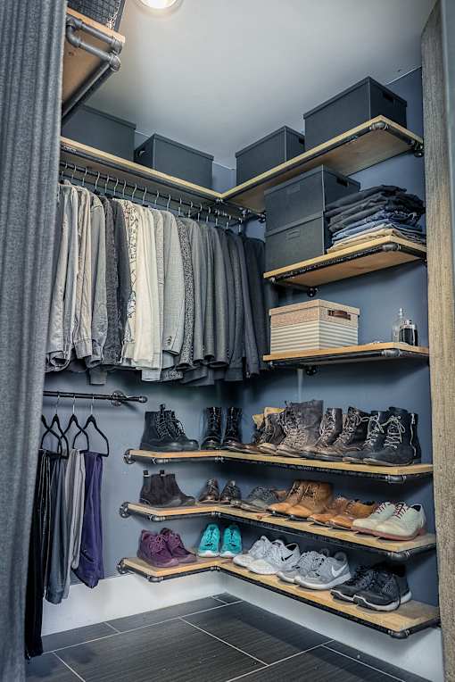 A walk in closet with clothes and shoes.