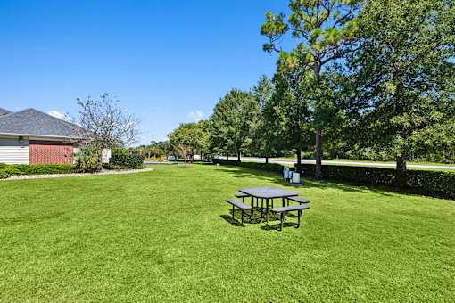 A picnic table sits in the middle of a grassy field.