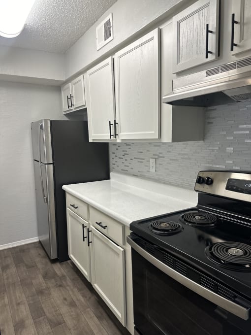 Open concept  kitchen with white cabinets and a stove and a refrigerator