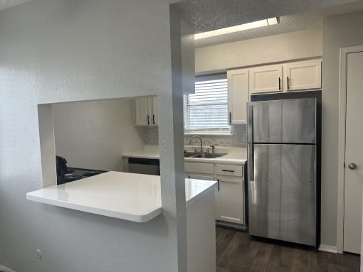 a kitchen with a white counter top and a stainless steel refrigerator