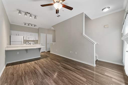 A room with a ceiling fan and a kitchenette.
