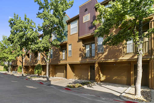 A row of brown apartment buildings with trees in front.