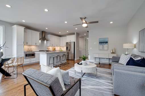 A modern living room with a kitchen in the background.