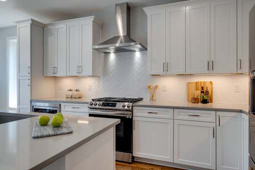 A kitchen with white cabinets and a stove top oven.