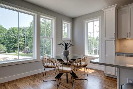 A dining table with four chairs is in the middle of a kitchen and living room.
