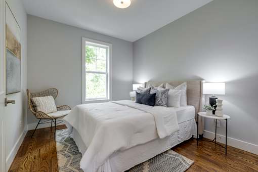 A bedroom with a bed, chair, and window.