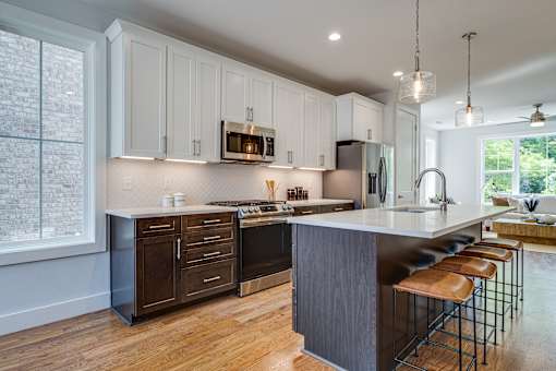A kitchen with wooden floors and a large island with stools.
