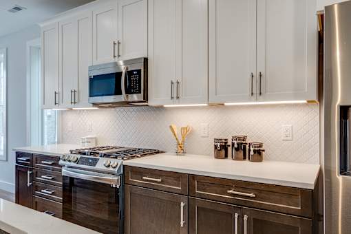 A kitchen with white cabinets and a stainless steel refrigerator.