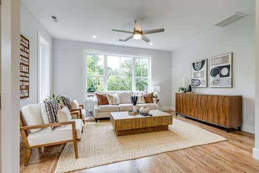 A living room with a white couch, a wooden coffee table, and a large window.