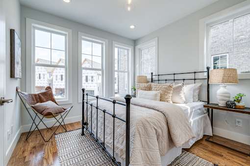 A bedroom with a large bed and a chair by the window.