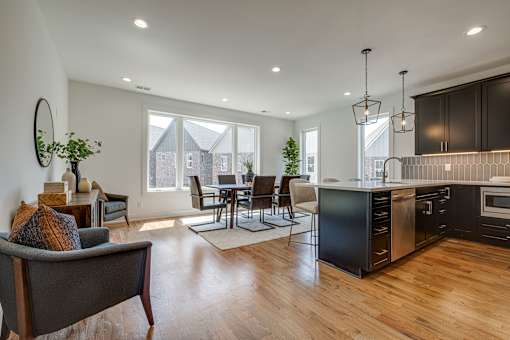 A modern kitchen with dark wood cabinets and a dining table with chairs.