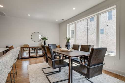 A dining room with a round mirror and a table with chairs.