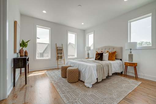 A bedroom with a large bed, a wooden chair, and a rug.