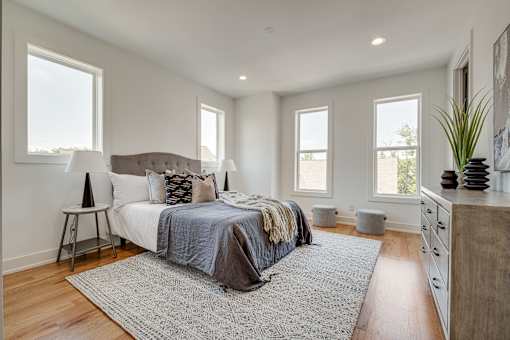 A bedroom with a large bed and a rug in the center.