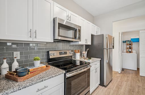 A kitchen with white cabinets and a black refrigerator.
