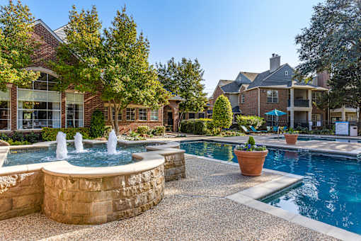 A pool with a fountain in the middle of a backyard.