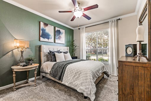 A bedroom with a bed, nightstand, and a ceiling fan.