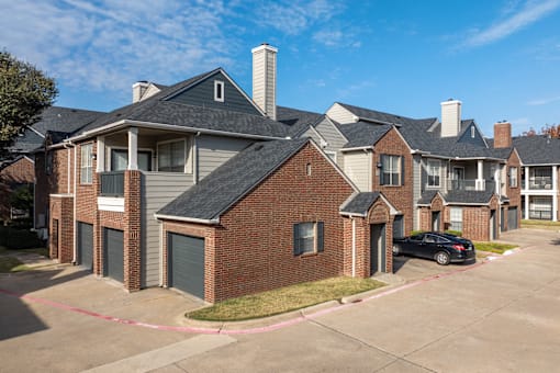 A black car is parked in front of a brick house.