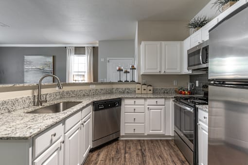 A modern kitchen with white cabinets and stainless steel appliances.