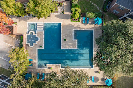An aerial view of a swimming pool surrounded by trees and a small building.