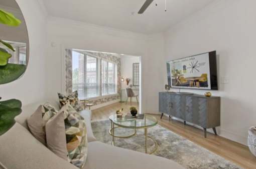 A living room with a grey cabinet, a glass table, and a painting on the wall.
