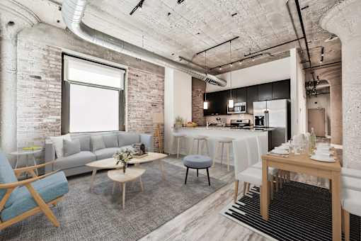A modern living room with a grey sofa, wooden chairs, and a dining table set for two.