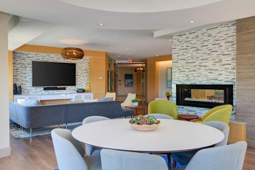 A modern living room with a stone fireplace and a large grey couch.