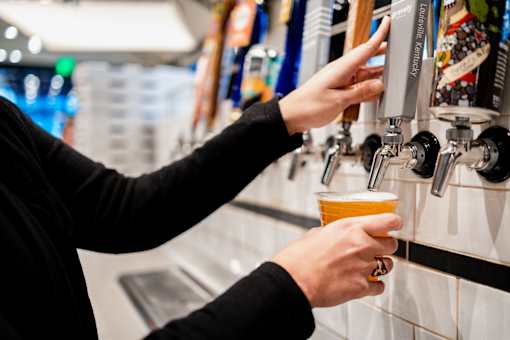 A person is pouring a beer from a tap into a cup.