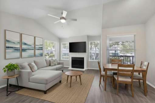 A living room with a grey couch, a fireplace, a television, and a dining table.