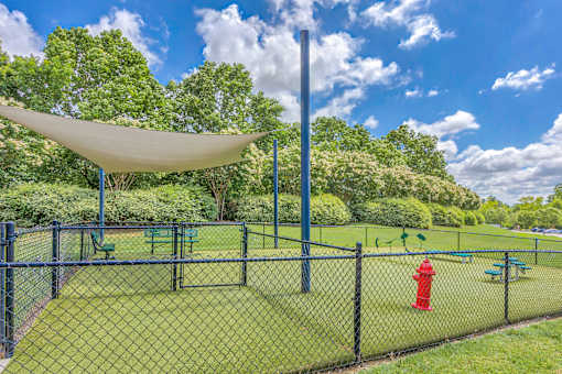 A playground with a green fence and a red fire hydrant.