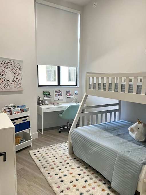A child's bedroom with a bunk bed, desk, and chair.