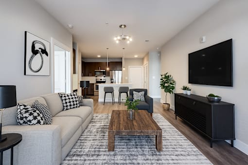 A modern living room with a grey couch, a wooden coffee table, and a black and white abstract painting on the wall.