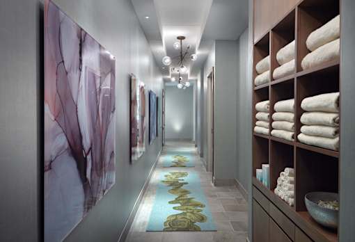 A hallway with a row of towels on the right and artwork on the wall.