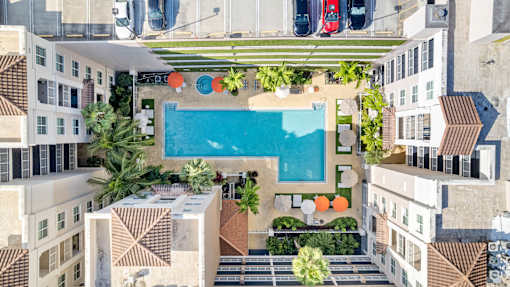 A swimming pool surrounded by palm trees and orange decorations in the middle of a courtyard.