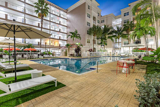 A pool area with a table and chairs and umbrellas.