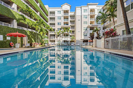 A swimming pool in front of a building with a white fence.