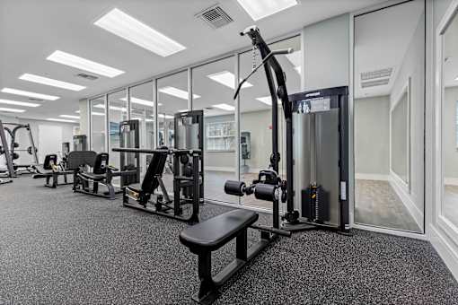 A gym with a variety of equipment including a squat rack, a leg press machine, and a cable machine.
