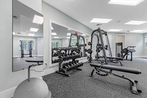 A gym with a mirror, weights, and exercise equipment.
