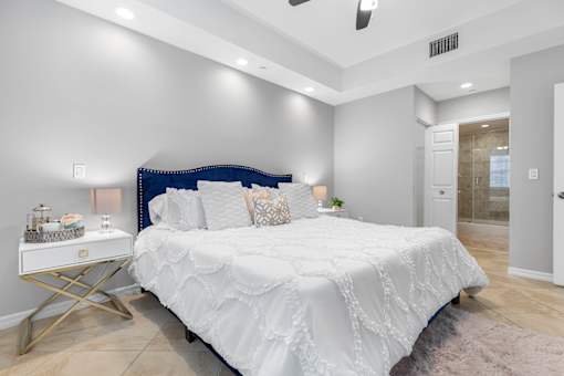 A bedroom with a white bed and a white nightstand.