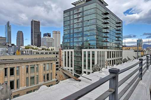 A modern glass building stands in front of a row of older buildings.