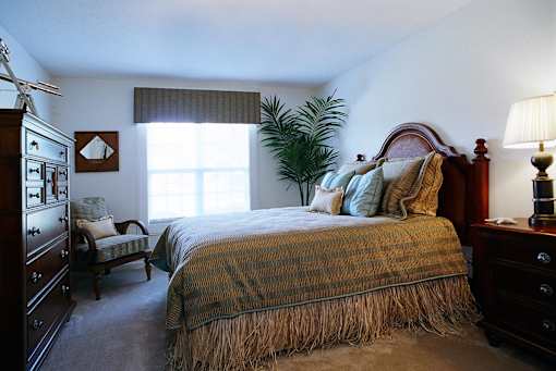 A bedroom with a bed, nightstand, and chair.