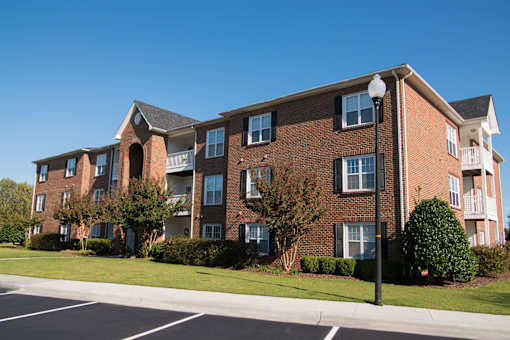 A large brick building with a parking lot in front.