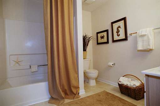 A bathroom with a toilet, a bathtub, a basket, and pictures on the wall.