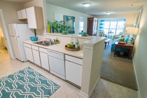 A kitchen with white cabinets and a blue patterned rug.