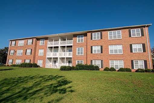 A red brick building with white balconies and windows.