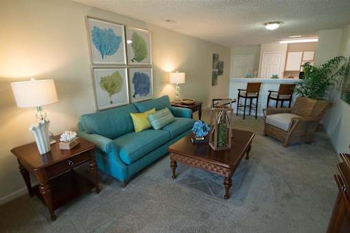 A living room with a blue couch, two end tables, and a chair.