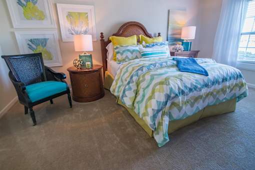 A bedroom with a bed, chair, and lamps.