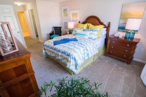A bedroom with a bed, nightstand, and dresser.